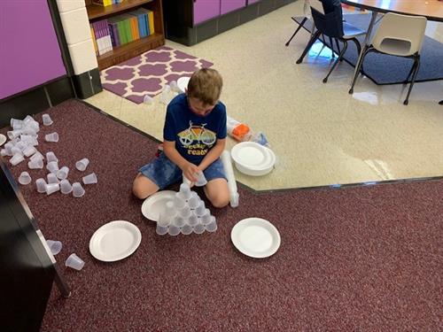 student building school from plastic cups